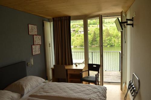 a hotel room with a bed and a desk and a window at Hotel Les Rives Du Doubs in Les Brenets