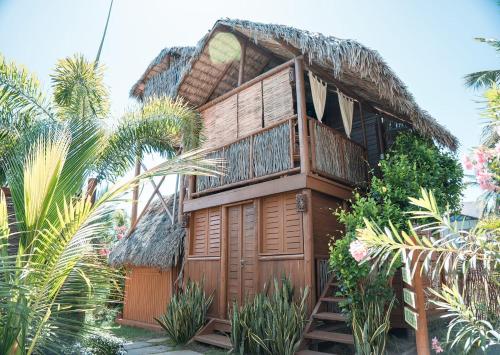 a house with a thatched roof and stairs to it at Pousada Villa del Lótus in Itarema