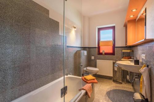 a bathroom with a tub and a sink and a toilet at Alpen Chalet Alte Talstation in Lenggries