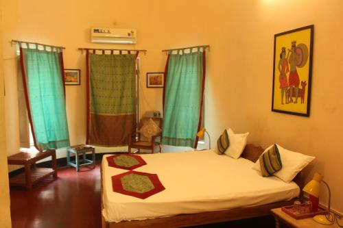 een slaapkamer met een bed met groene gordijnen bij Cozy Inn in Varanasi