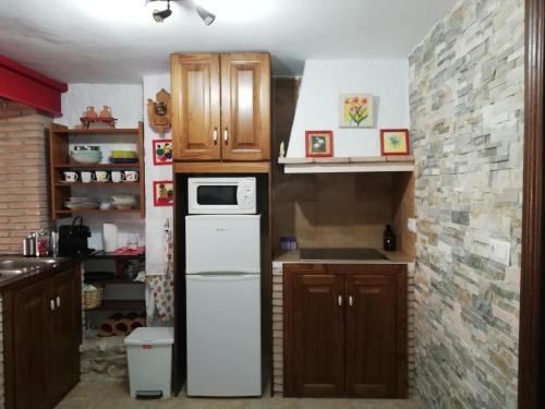 uma cozinha com um frigorífico branco e armários de madeira em La casa de Tento em Tózar