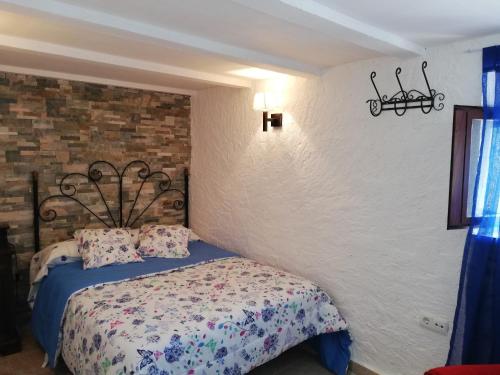 a bedroom with a bed and a brick wall at La casa de Tento in Tózar
