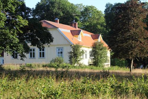 a white house with an orange roof in a field at Yxkullsund Säteri B&B - Manor & Estate since 1662 in Lagan