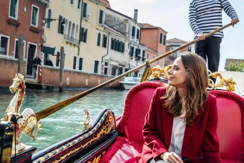 a girl is sitting in a gondola on a canal at Baglioni Hotel Luna - The Leading Hotels of the World in Venice