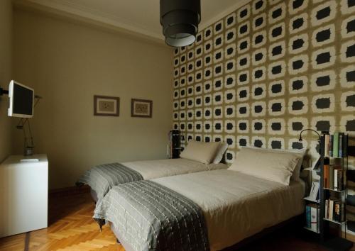 two beds in a bedroom with a wall of pictures at Casatitta Bed & Breakfast in Milan