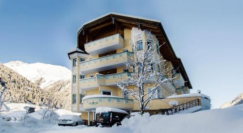 a large building in the snow with a tree at Hotel Garni Waldschlössl in Ischgl