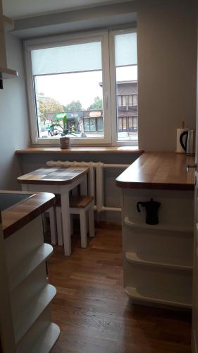 een keuken met een bureau, een tafel en een raam bij Kurzemītes apartamenti in Kuldīga