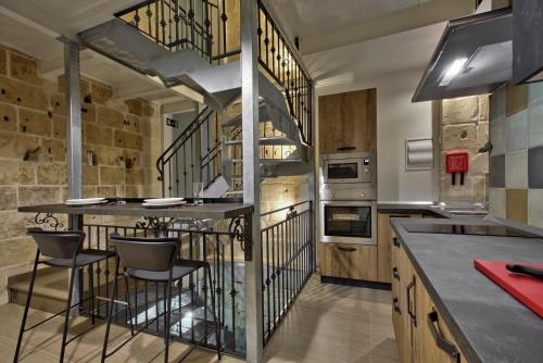a kitchen with a bar with chairs and a staircase at Chateau La Vallette - Tritoni Suite in Valletta