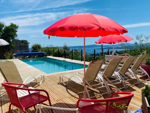 een groep stoelen en een rode parasol naast een zwembad bij Villa Marcelline Belle vue mer Golfe de Saint Tropez in Saint-Peïre-sur-Mer