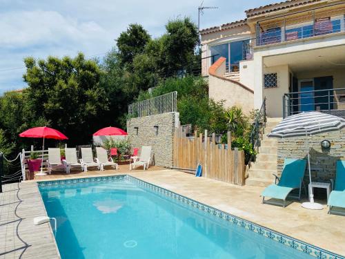una piscina con sedie e ombrelloni accanto a una casa di Villa Marcelline Belle vue mer Golfe de Saint Tropez a Saint-Peïre-sur-Mer