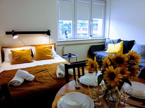 ein Zimmer mit einem Bett und einem Tisch mit Blumen darauf in der Unterkunft Orange Apartament in Wadowice