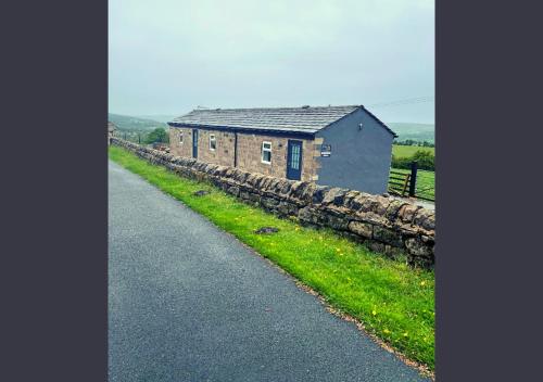 a house on the side of a road next to a stone wall at Chevin End Guest House in Otley