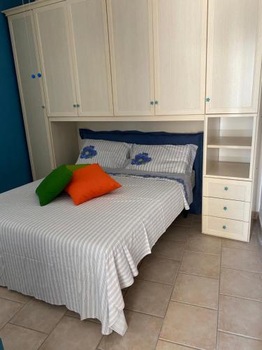 a bedroom with a bed with white cabinets and an orange pillow at casa patrizia in Villanova di Ostuni