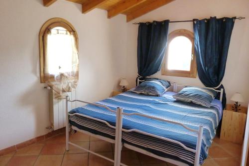 um quarto com uma cama com lençóis azuis e duas janelas em Villa de 4 chambres avec piscine privee terrasse amenagee et wifi a Breil sur Roya em Breil-sur-Roya