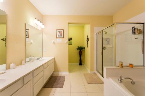 La salle de bains est pourvue de 2 lavabos et d'une douche. dans l'établissement 4Br 2Bath Condo Balcony 5min Conv Center 2020ft, à Orlando