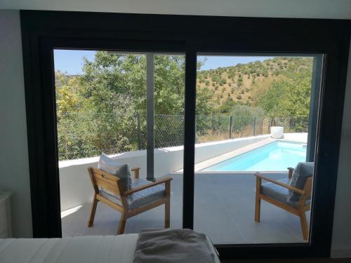 1 dormitorio con vistas a la piscina y 2 sillas en Moderna casa rural en El Bosque con piscina y preciosas vistas, en El Bosque