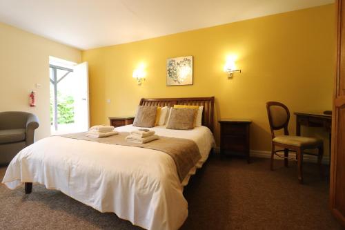 a bedroom with a large bed with yellow walls at St George's Lodge, Bisley in Brookwood