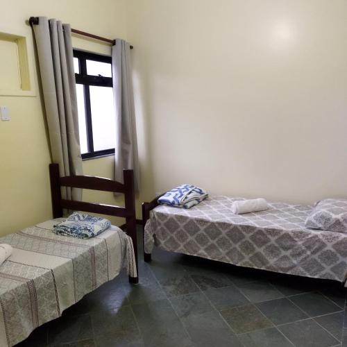 two beds in a room with a window at Dom Yargo II in Arraial do Cabo