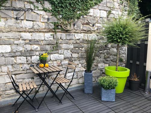 a patio with a table and chairs and a stone wall at Mademoiselle Citadelle in Namur