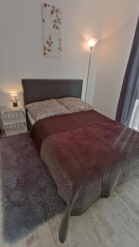 a bedroom with a bed with a blanket and a lamp at Apartament na Kruczej in Lubin