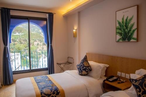 a hotel room with two beds and a window at VANCII Hotel in Chefchaouene