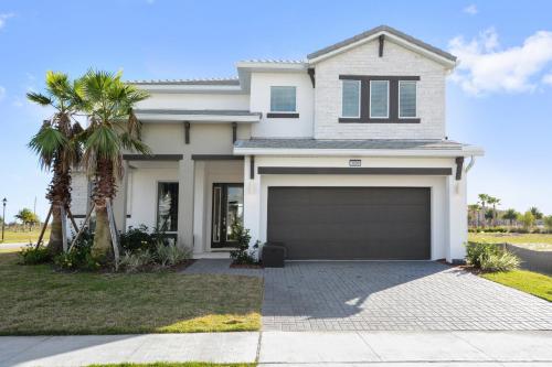 a white house with a garage and a palm tree at 5Br 5Bath Pvt Home BBQ Pool 15min Disney 3056ft in Kissimmee
