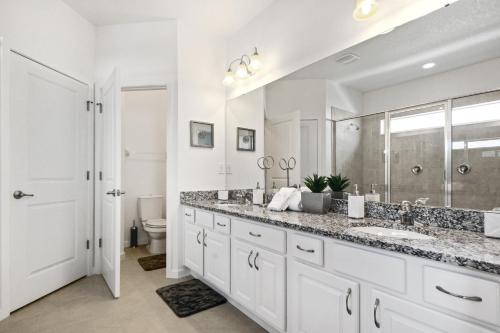 uma casa de banho branca com um lavatório e um chuveiro em 5Br 5Bath Pvt Home BBQ Pool 15min Disney 3056ft em Kissimmee