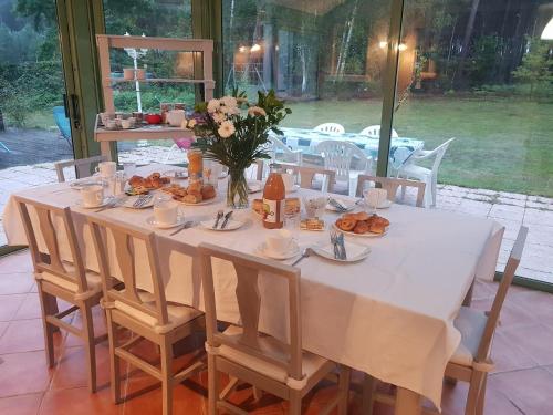 une table blanche avec des chaises et une table avec de la nourriture dans l'établissement B&B La Forêt de Charmeuse, à Ruaudin