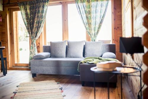 a living room with a blue couch and windows at Leśna Osada przy Suntago Park in Krzyżówka