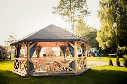 a wooden gazebo in a park with a playground at Leśna Osada przy Suntago Park in Krzyżówka