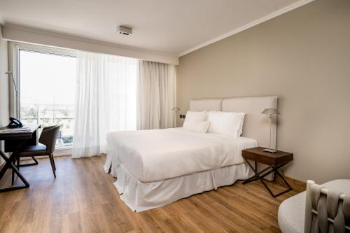 1 dormitorio con 1 cama blanca grande y escritorio en Hotel Solerios, en Punta del Este