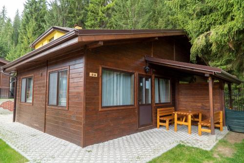 a small wooden cabin with a table in front of it at Почивна станция Сомат in Dospat