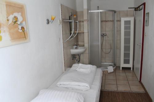 a bathroom with a sink and a shower with white towels at Hotel Lilienhof in Hamburg