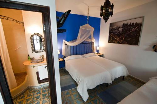 Schlafzimmer mit einem weißen Bett und einem Spiegel in der Unterkunft Riad Assilah Chaouen in Chefchaouen