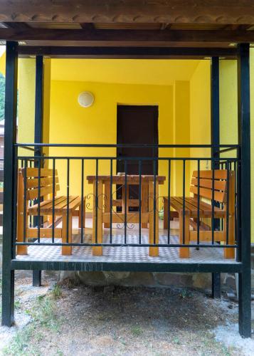 a yellow house with a table and chairs at Почивна станция Сомат in Dospat