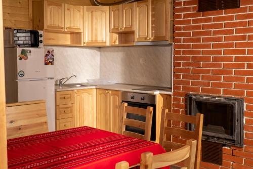 a kitchen with a table and a brick wall at Почивна станция Сомат in Dospat
