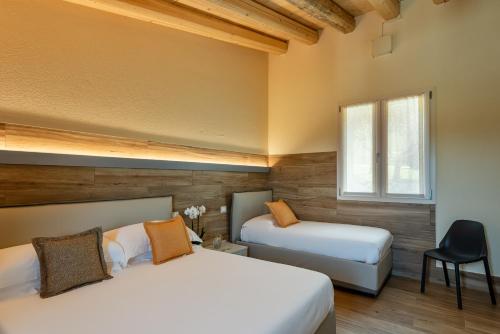 a bedroom with two beds and a chair and a window at Sporting Hotel San Felice in Illasi
