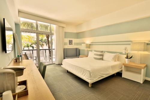 um quarto com uma cama branca e uma grande janela em The Local House em Miami Beach