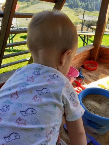 a baby boy playing with sand in a sandbox at 4 Mountains Apartments in Kleinarl