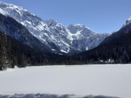 a snow covered mountain range with a lake in the foreground at 4 Mountains Apartments in Kleinarl