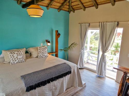 a bedroom with a large bed with blue walls at Il Tano Suites in Punta Del Diablo