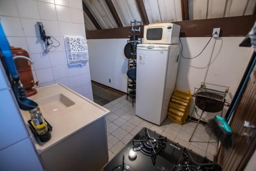 a kitchen with a refrigerator and a microwave on top of it at Chalés da Cuesta in Pardinho