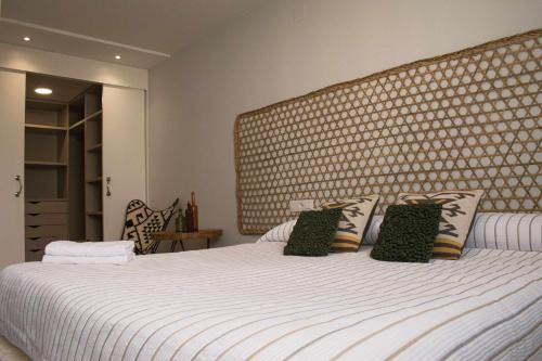 - une chambre avec un lit blanc et une grande tête de lit dans l'établissement Apartamento Dúplex Estación Manzaneda, à Ourense