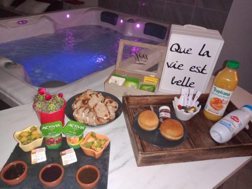 une table avec de la nourriture et des boissons et une piscine dans l'établissement Nuit romantique avec Jacuzzi SPA privatif proche TOULOUSE, à Auterive