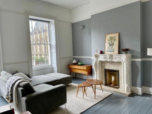 a living room with a couch and a fireplace at Grand & Graceful One Bed Flat in Clifton Village in Bristol
