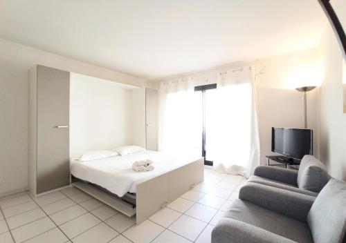 une chambre avec un lit, un canapé et une télévision dans l'établissement Viva Riviera - Studio Jardin Florian, à Cannes