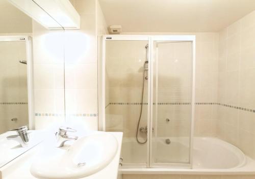 une salle de bain blanche avec une douche et un lavabo dans l'établissement Viva Riviera - Studio Jardin Florian, à Cannes