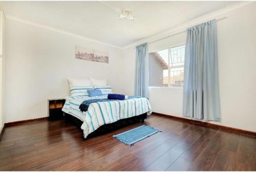 a white bedroom with a bed and a window at The Resting Nest in Midrand