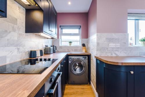 a kitchen with a washer and a washing machine at Castle Views cottage in historic village & woodfired hot tub in Rhuddlan