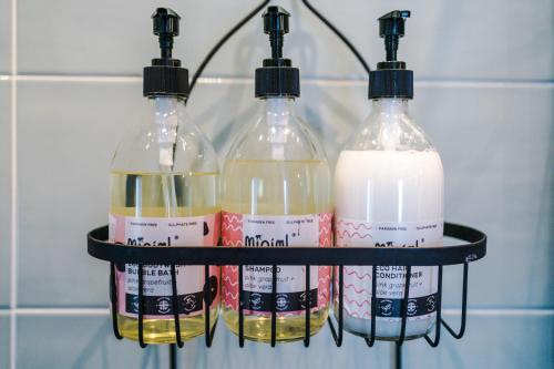 three bottles of milk on a shelf in a bathroom at Castle Views cottage in historic village & woodfired hot tub in Rhuddlan
